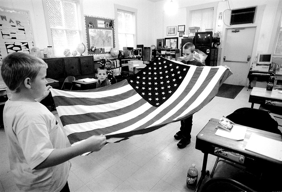 Sixth grader, Cody Farrell, 11, left, and Kyle Sirk 12, a seventh grader, fold the American flag after bringing it in from the rain, Wednesday morning at Wood School, in Bangor Township. From putting