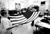 Sixth grader, Cody Farrell, 11, left, and Kyle Sirk 12, a seventh grader, fold the American flag after bringing it in from the rain, Wednesday morning at Wood School, in Bangor Township. From putting